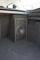 I built a narrow upright cabinet, to be installed against the back seat, and neatly fitting under the roller cover bar. It's a closed cab of around 15 liters, which gives a nicely damped response with a Q of around .65. I wrapped it in self adhesive black carpet and used the (trimmed) steel grill I took out of the old sub.